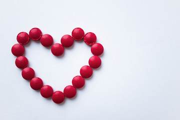 The red tablets are arranged in the shape of a heart. Red heart pills. The concept of a healthy heart. Vitamins for the heart.
