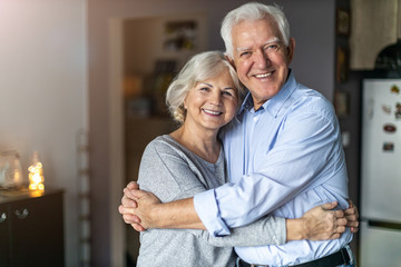 Happy senior couple embracing in their home  - obrazy, fototapety, plakaty