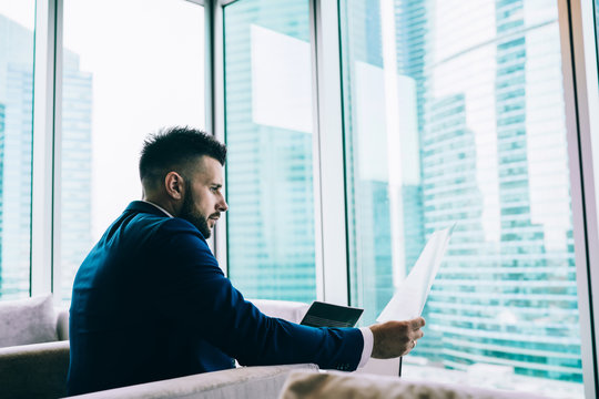 Male Employee In Formal Wear Reviewing Documents At Office