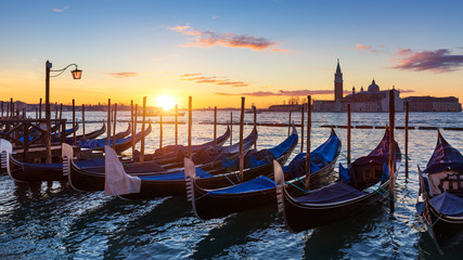 Venice with famous gondolas at sunrise, Italy. Gondolas in lagoon of Venice on sunrise, Italy. Venice with gondolas on Grand Canal against San Giorgio Maggiore church.
