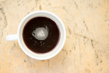 A white cup and black coffee on table ground