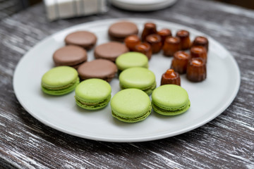 Cookies of pasta, green and brown colors, as well as other sweets, are laid out on a plate.