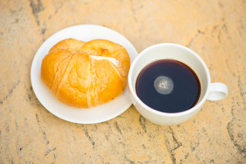 A white cup and black coffee with Croissant with cheese