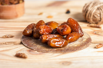Tasty dates on a round substrate close-up on a wooden background