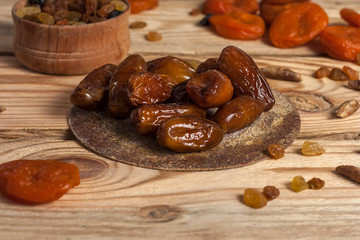 Tasty dates on a round substrate close-up on a wooden background