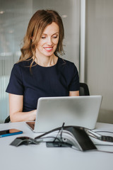 Naklejka premium Portrait of modern beautiful smiling business woman working at her laptop happily. Online meeting. Good news. Coworking space