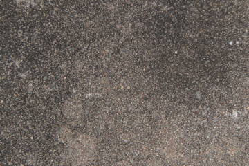 The surface of the concrete road has small grains of sand and black stains.