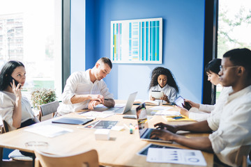 Concentrated multiracial coworkers using gadgets at meeting