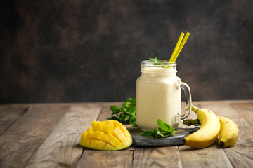 Delicious mango smoothie in mason jar on a rustic background. Healthy food, detox diet. Copy space..