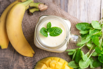 Delicious mango smoothie in mason jar on a rustic background. Healthy food, detox diet. Copy space..