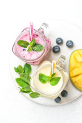 Delicious blueberry and mango smoothie in mason jar on a light background. Healthy food, detox diet. Copy space.