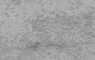 The surface of the concrete road has small grains of sand and black stains.