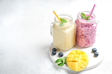 Delicious blueberry and mango smoothie in mason jar on a light background. Healthy food, detox...