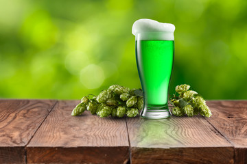 Still life with glass of fresh green beer and hops.