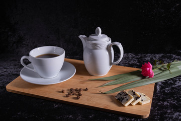a cup of coffee and a kettle stand on a tray.
