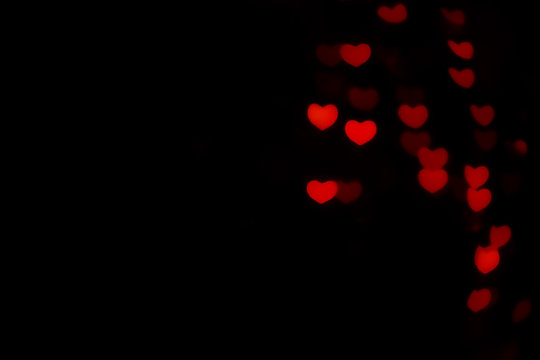 Abstract beautiful romantic picture of blur brightness red colored of swirling heart shaped bokeh on black from ornamental lights flickering. Background for Valentine’s day or Love or Romance concept.