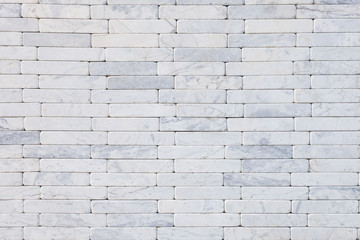 White natural stone marble brick masonry wall outside of the building. Rough surface texture exterior of stone wall. Design and decoration concept with copy space for text.