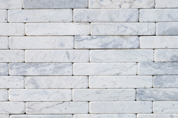 White natural stone marble brick masonry wall outside of the building. Rough surface texture exterior of stone wall. Design and decoration concept with copy space for text.