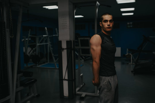 Handsome man with big muscles, posing at the camera in the gym