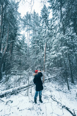 Female photographer takes pictures in snow forest