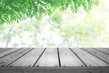 Wooden table and blurred green leaves nature background.