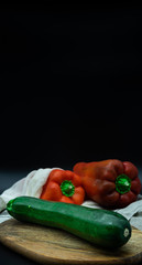 Red pepper and zucchini in an organic cotton bag, on a wooden board, black background, zero waste concept