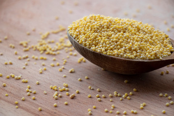 Yellow millet porridge on a wooden board. Wooden spoon on a white background. Healthy food, best breakfast. Take care of your body.