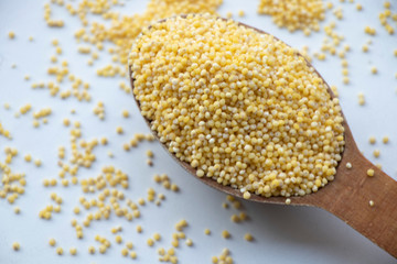 Yellow millet porridge on a wooden board. Wooden spoon on a white background. Healthy food, best breakfast. Take care of your body.