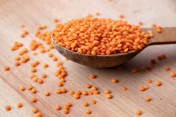 Orange lentils on a wooden board. Wooden spoon on a white background. Healthy food, best breakfast.