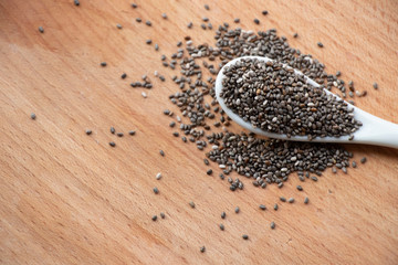 Chia seeds on a ceramic small spoon. Wooden spoon on a white background. Healthy food, best breakfast.