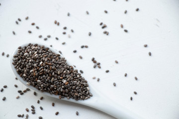 Chia seeds on a ceramic small spoon. Wooden spoon on a white background. Healthy food, best breakfast.