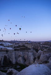 Fototapeta na wymiar Cappadocia, Turkey, Europe: hot air balloons floating at dawn and view of the valley around Cavusin, town of the historical region in Central Anatolia rich of exceptional natural wonders
