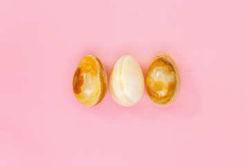 Yellow stone Easter eggs close up. Minimal style composition with Easter design concept. Pastel colors and pink background. Top view.