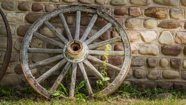 Old cartwheel by the stone wall of an old building