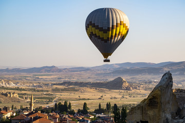 Cappadocia, Turkey, Europe: a traditional hot air balloon floating after dawn in the sky over the valley of Cavusin in the historical region in Central Anatolia rich of exceptional natural wonders