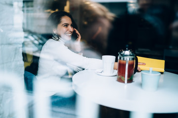 Excited female calling on smartphone in cafe