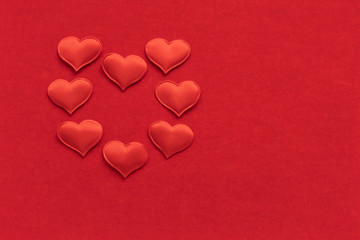 8 small textile red hearts are in the shape of a large heart on a background of red velvet paper