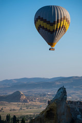 Cappadocia, Turkey, Europe: a traditional hot air balloon floating after dawn in the sky over the valley of Cavusin in the historical region in Central Anatolia rich of exceptional natural wonders
