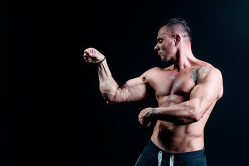 Obraz na płótnie Canvas Male bodybuilder with an athletic build on a dark background.athlete, exercise, health, power, strength, man,