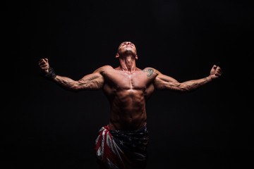 Fototapeta na wymiar Male bodybuilder with an athletic build on a dark background. athlete, exercise, health, power, strength, man,