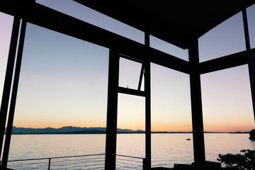 Luxury home windows with view of sunset over mountains and water. 