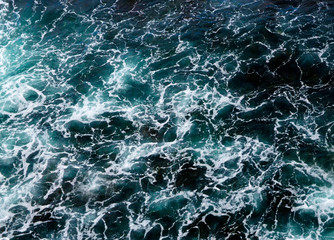 Abstract blue ocean water with white foam background.Sea waves  texture.Selective focus.