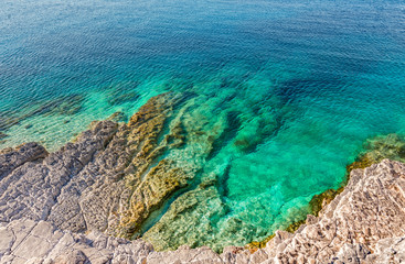 Aerial view of  turquoise calm sea  against rocks. Wonderful beauty wild beach with stony rocky shore, shallow sea water. Beautiful scenery and sunny day on Kefalonia Island, Greece. Natural texture