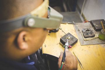 Close up image of a jeweler making jewelery with traditional hand tools in a jewelery shop.