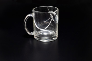 Broken cup isolated on a black, cracked glass