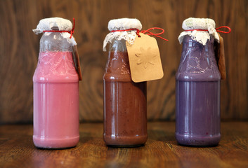 colorful Smoothies at the bottles. Colorful drink, milk shake in bottle with fresh vegetables and superfoods on a wooden background.
