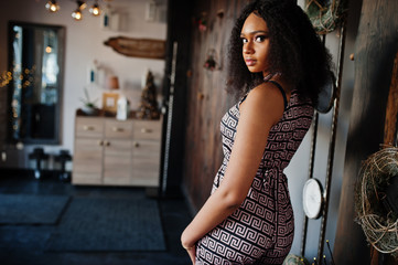 Fototapeta na wymiar Сharming elegant young african american woman with long curly hair wearing jumpsuit posing at cafe indoor.