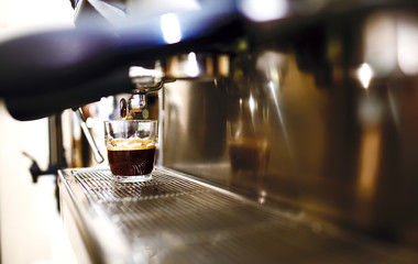 Black coffee morning on coffee maker. Coffee machine preparing fresh coffee and pouring into cups at restaurant, bar or pub. Professional brewing. Preparation service concept.