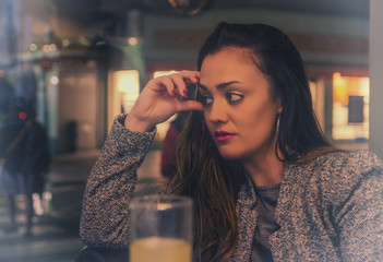 Mujer pensativa en una cafetería junto a la ventana