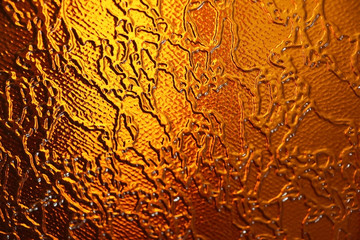Colored glass. Gold and brown background. The texture of the glass. Yellow patterns. Design.